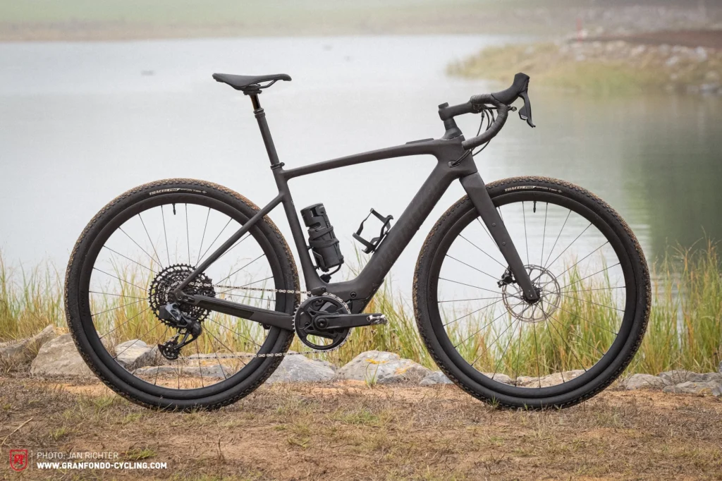 Specialized gravel bike in black parked beside a scenic lake backdrop.