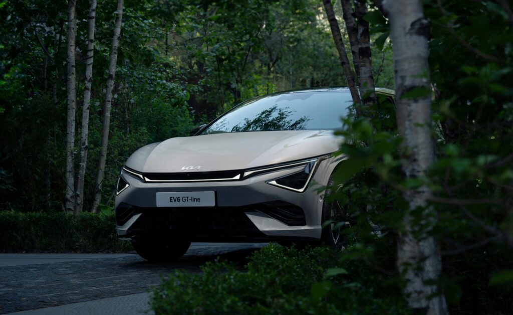 Kia EV SUV parked in a serene forest setting.