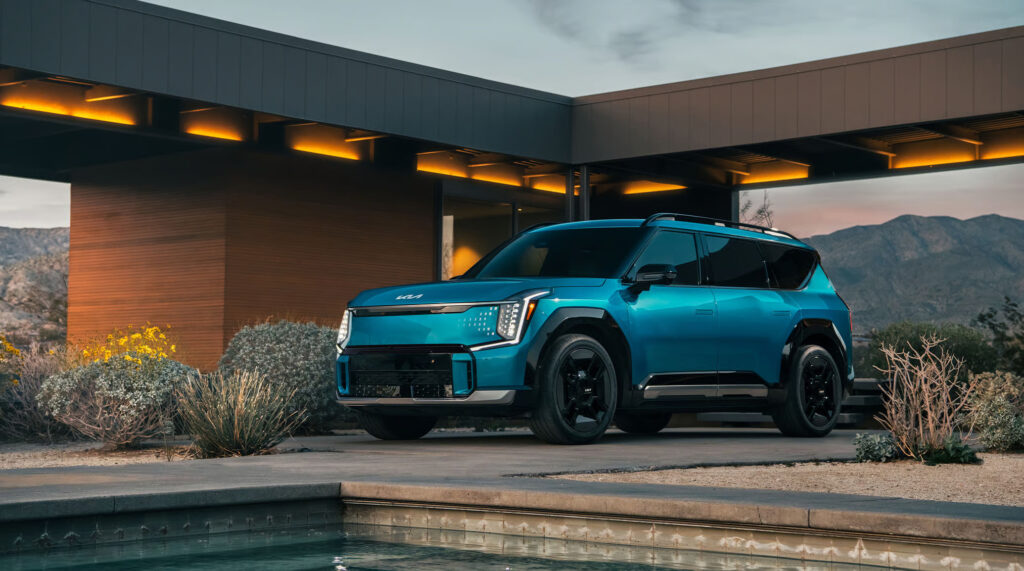 Kia EV9 2025 electric SUV beside a luxury modern house.