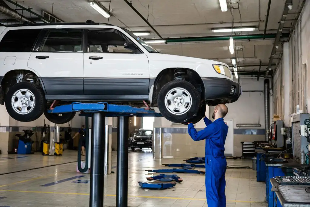 Mechanic inspecting lifted SUV during routine service car maintenance tips for beginners.