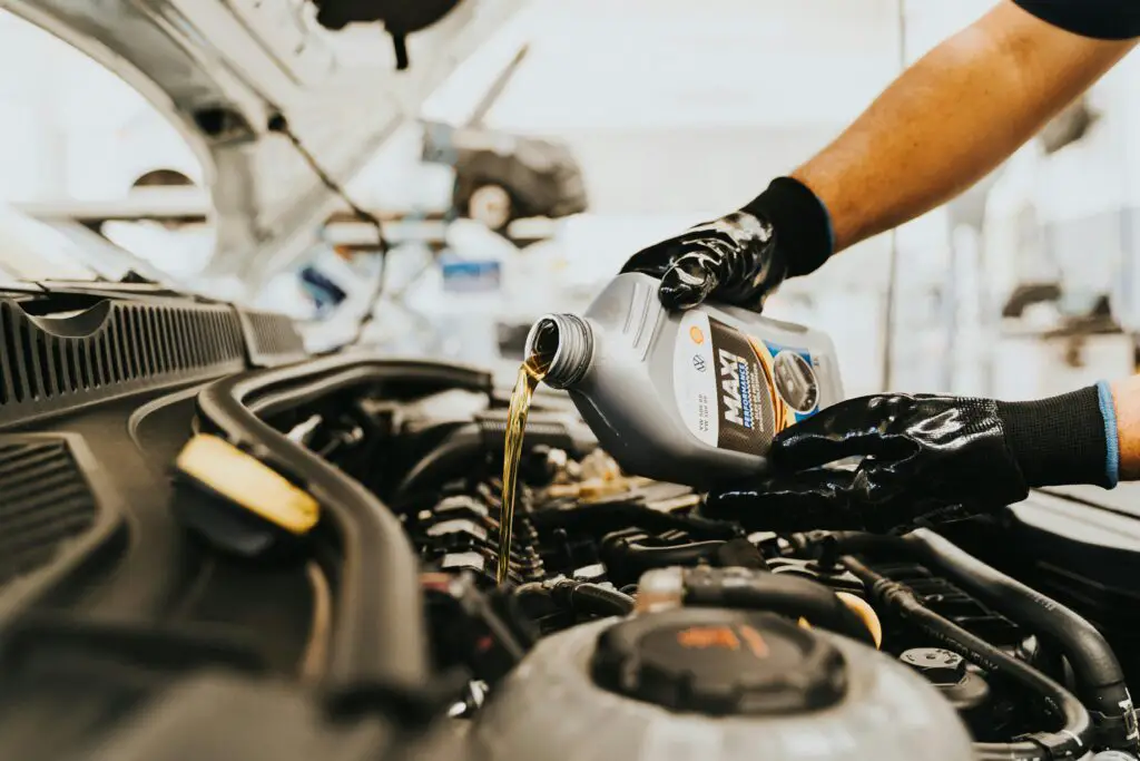 Mechanic pouring fresh engine oil into car engine - car maintenance tips for beginners.