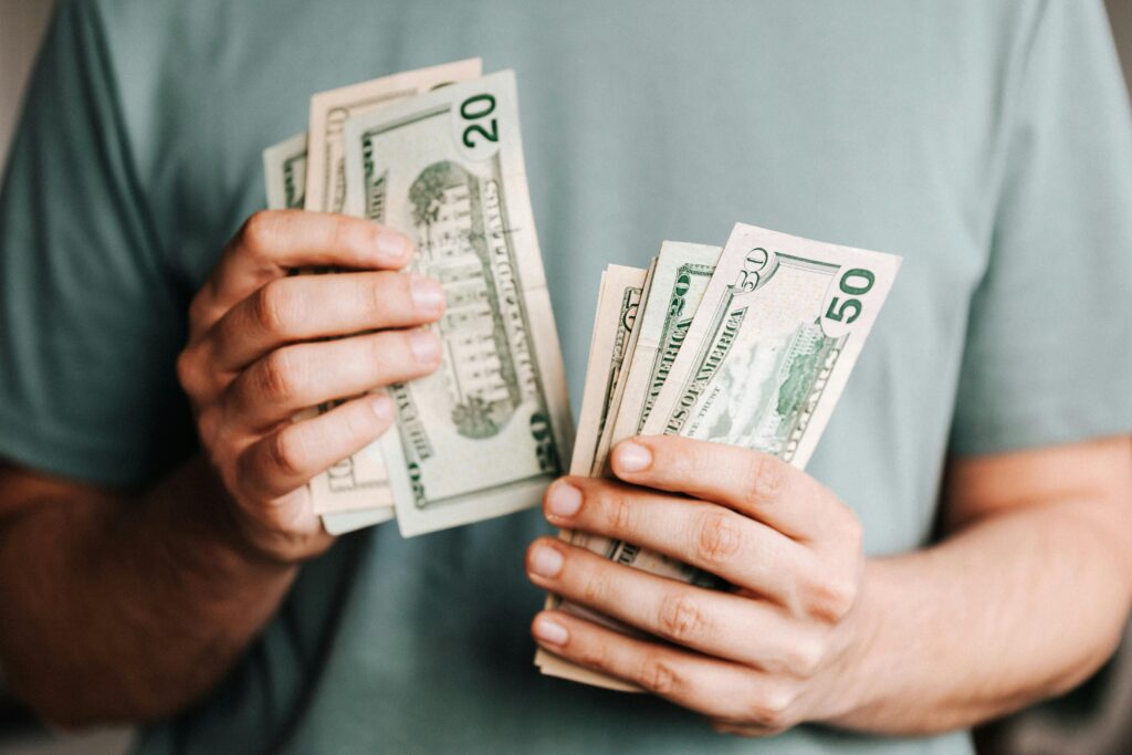 Person holding U.S. dollars symbolizing 2025 Mazda CX-5 Hybrid review with rebate tax and high resale value.