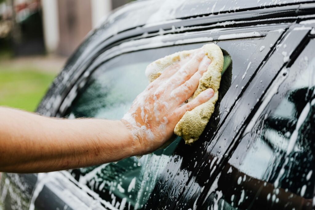 Hand scrubbing car window with sponge and soap – best car wash near me in California