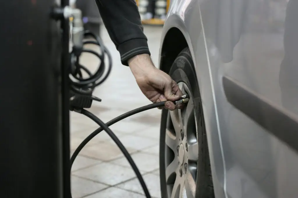 Mechanic checking car tire pressure with air gauge – car maintenance tips for beginners.