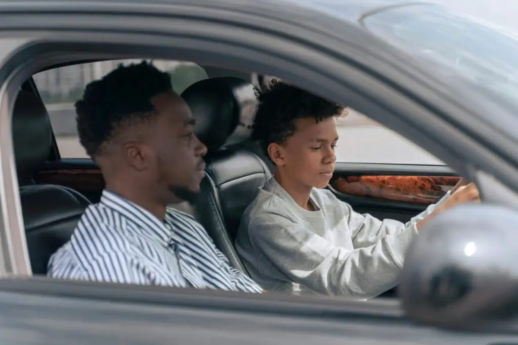 Teenage driver with instructor practicing driving for best car insurance for young drivers.