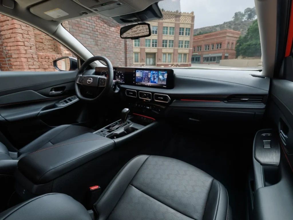 Interior dashboard of the 2026 Nissan Sentra introducing the dual 12.3-inch screens, leather seating, and red stitching inside the compact sedan.