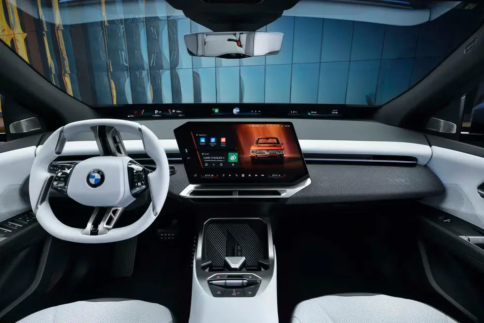 Interior of the BMW iX3 2026 showing the white steering wheel, large central infotainment screen, and modern dashboard layout.