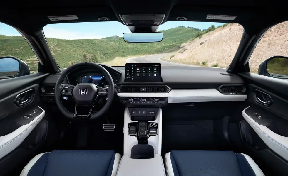 The Honda Prelude 2026's cabin is black and white, has a touchscreen display, and a modern steering wheel for a high-end driving experience.